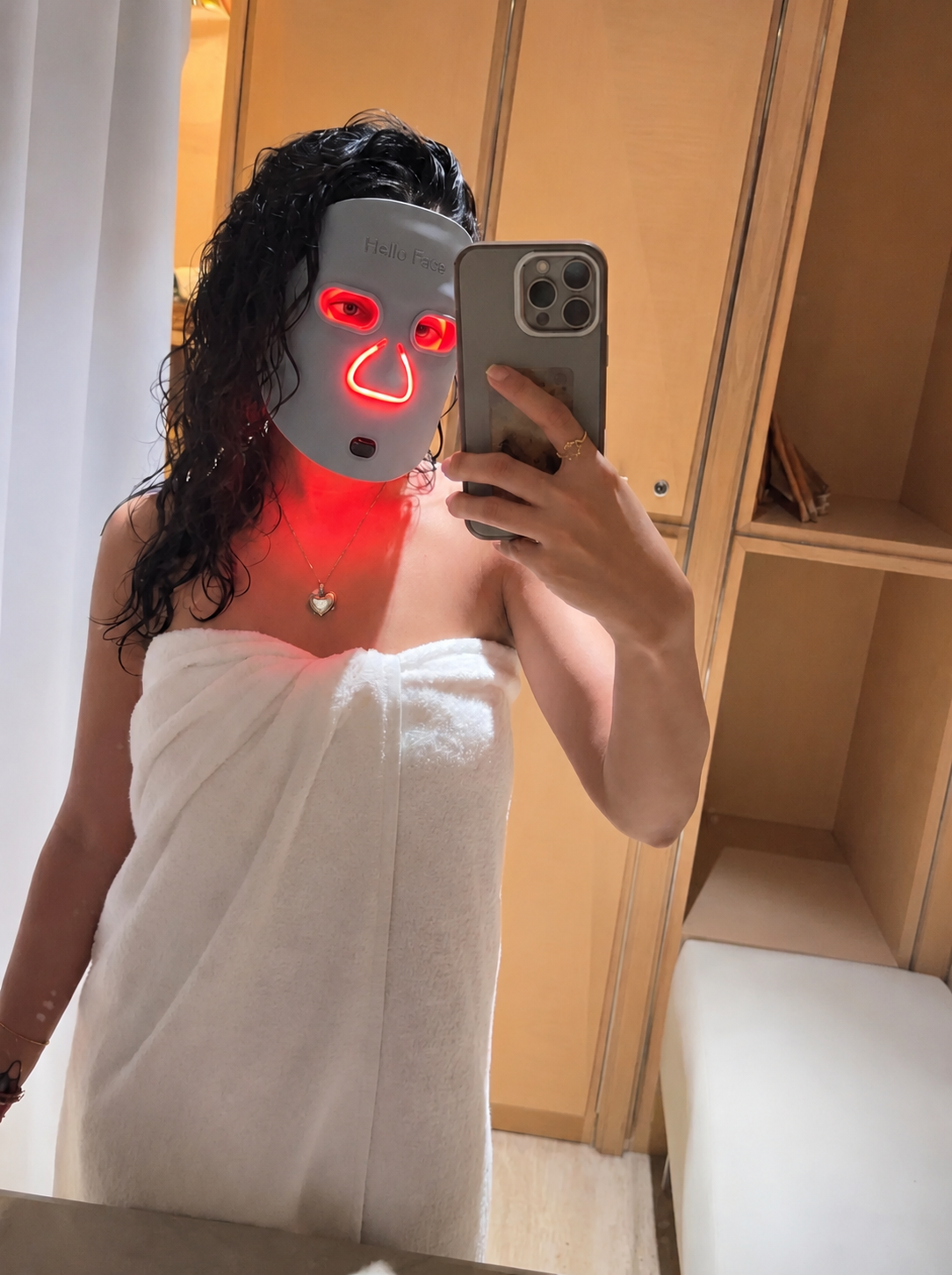 Woman wearing the Louvaine LED mask at home after a shower